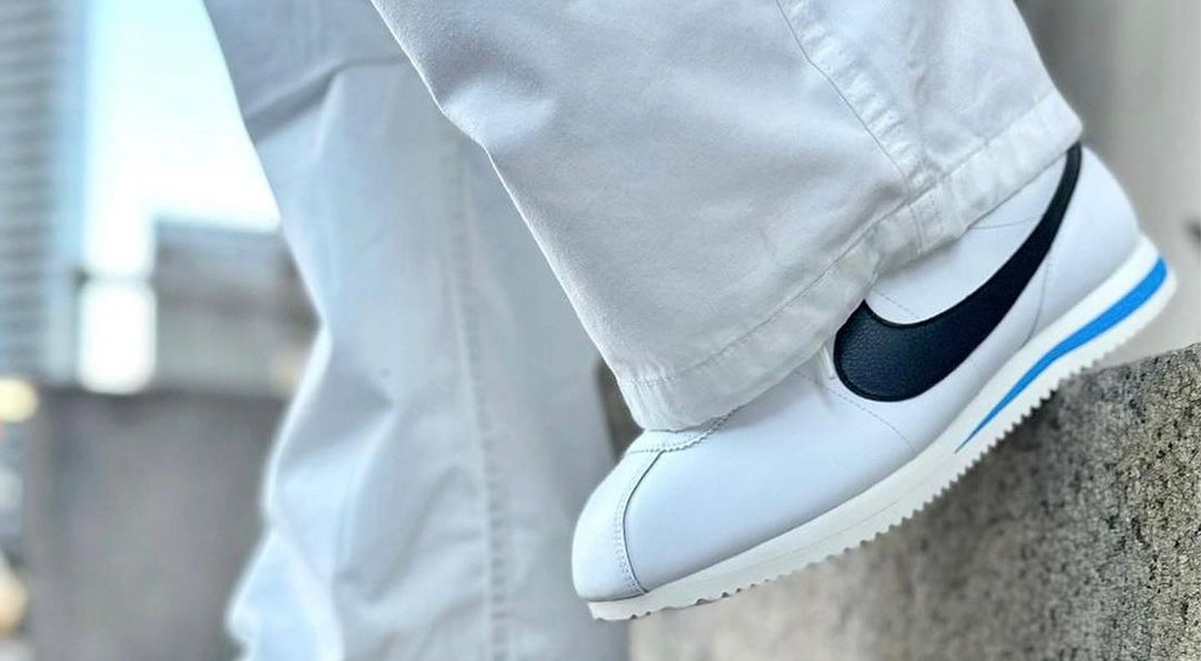 Nike cortez on feet paired with white wide pants on a step. 